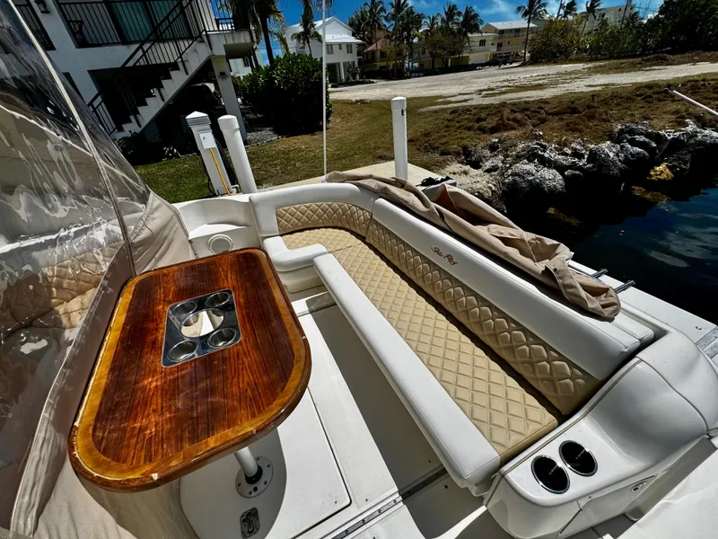 Slide: The Image of 2001 Sea Ray 460 Sundancer boat interior with cushioned seating and wooden table. - 28