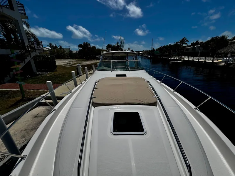 Slide: The Image of 2001 Sea Ray 460 Sundancer yacht docked, featuring spacious deck and sunpad under clear blue sky. - 30