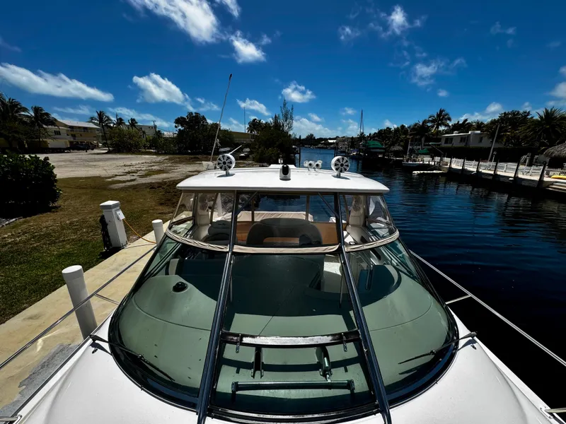 Slide: The Image of 2001 Sea Ray 460 Sundancer yacht docked by a scenic waterfront under a clear blue sky. - 32