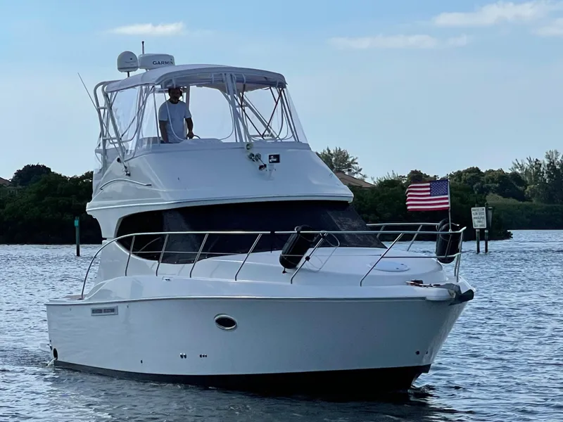 Slide: The Image of 2007 Silverton 33 Convertible yacht cruising on a calm waterway with American flag. - 2