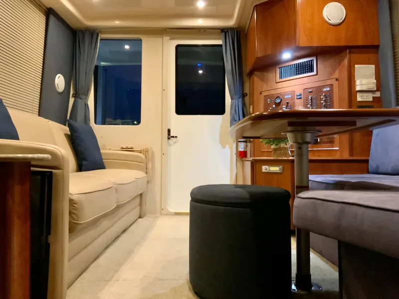 Slide: The Image of Interior of a 2007 Silverton 33 Convertible yacht, featuring cozy seating and elegant wood paneling. - 31