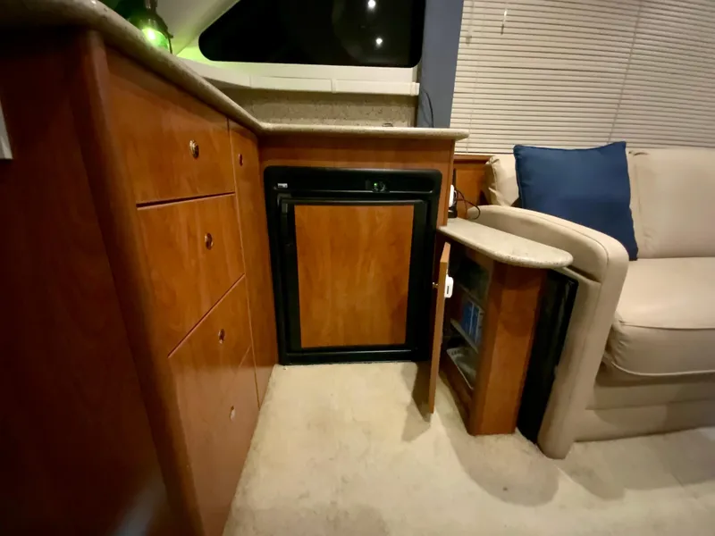 Slide: The Image of 2007 Silverton 33 Convertible interior with wooden cabinetry, mini fridge, and beige seating. - 39