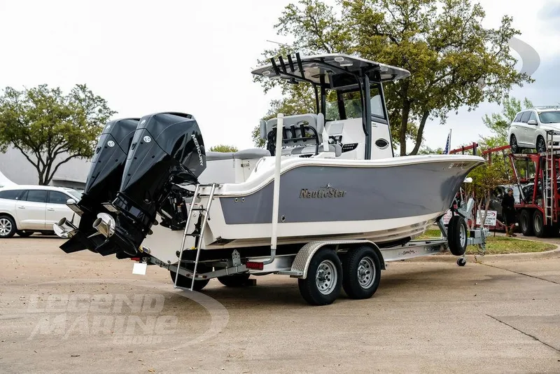 Slide: The Image of 2022 NauticStar 2602 Legacy boat on trailer, dual outboard engines, parked outdoors. - 4