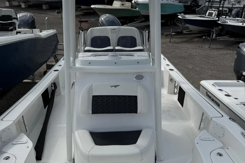 Slide: The Image of 2025 Tidewater 2210 Carolina Bay boat interior with seating and console, in a marina setting. - 10