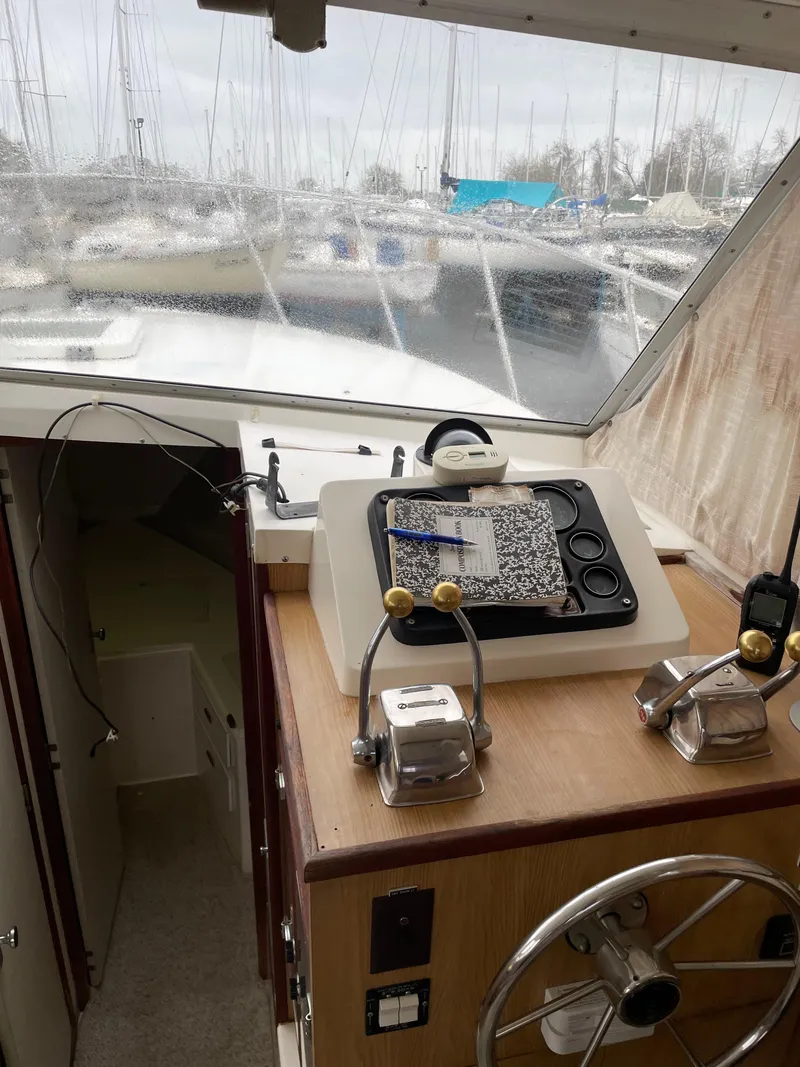 Slide: The Image of 1978 Bertram 33 Flybridge Cruiser helm with controls and marina view. - 17