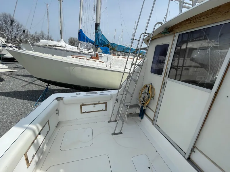 Slide: The Image of 1978 Bertram 33 Flybridge Cruiser, docked with visible deck and ladder. - 8