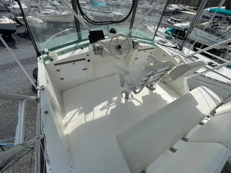 Slide: The Image of 1978 Bertram 33 Flybridge Cruiser cockpit with steering wheel and seating, docked among other boats. - 9