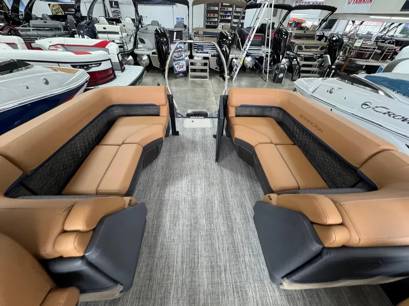 Slide: The Image of 2025 Bennington 24 MFB boat interior with tan seating, displayed in a showroom. - 6