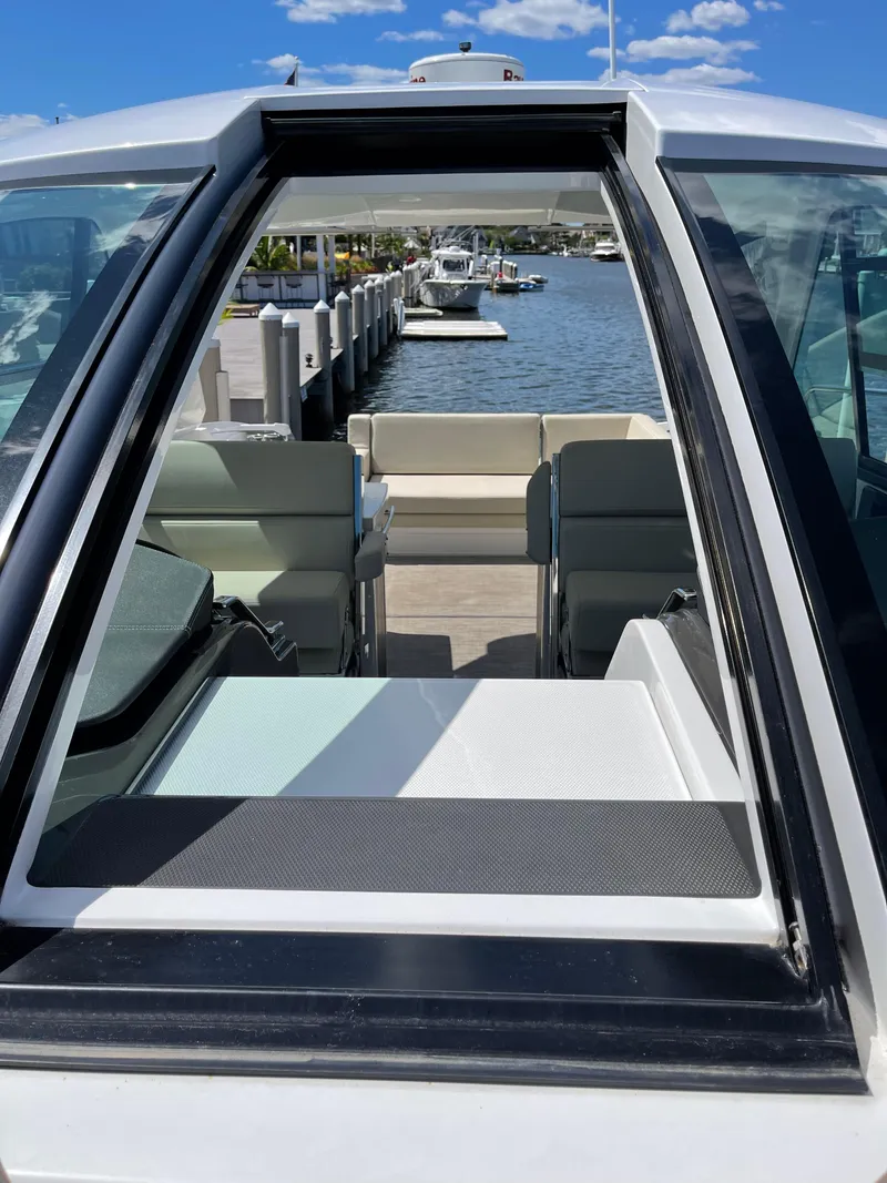 Slide: The Image of Interior of a 2017 Monterey 360 Sport Coupe boat with white seating and marina view. - 12