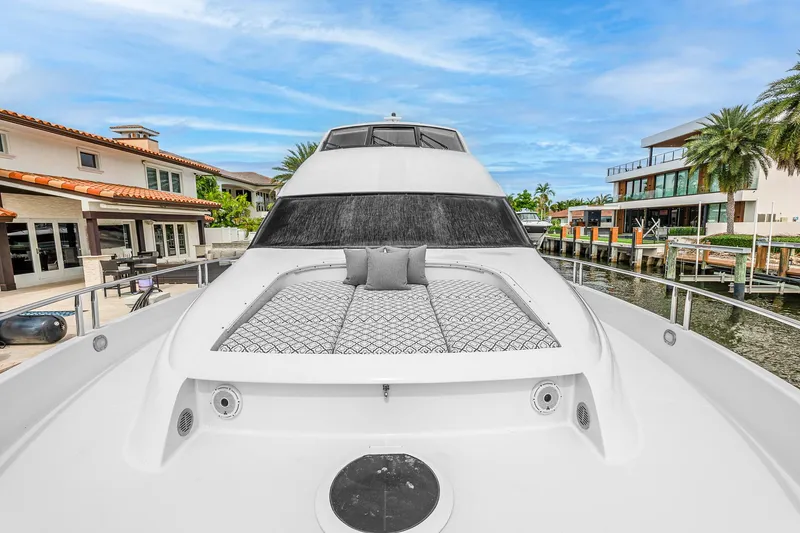 Slide: The Image of 2002 Lazzara 80 Skylounge yacht with sunbathing area, docked near luxury waterfront homes. - 6