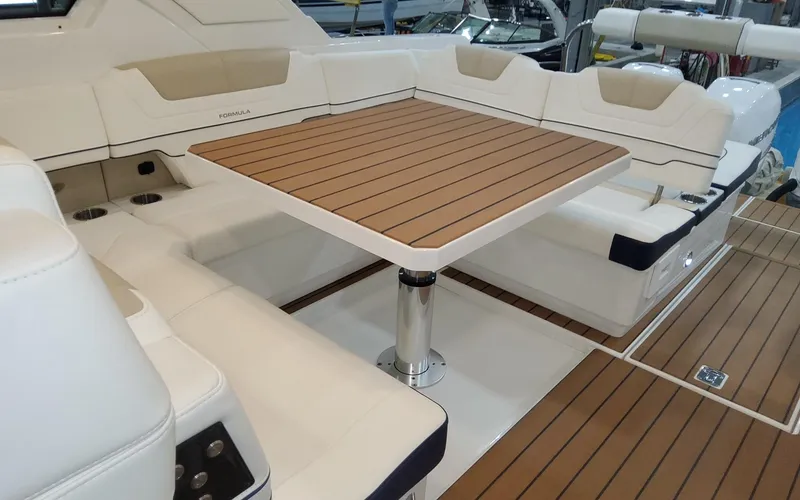 Slide: The Image of 2022 Formula 400 Super Sport Crossover boat interior with teak table and white seating. - 12