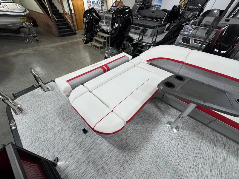Slide: The Image of 2025 Bennington 24 ML pontoon boat interior with white and red seating, gray flooring, and table. - 12