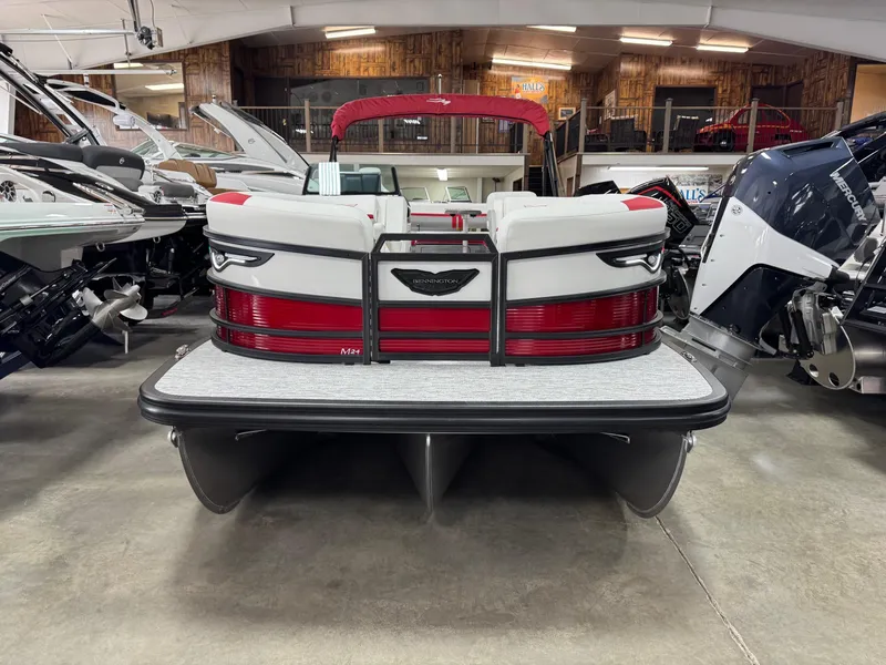 Slide: The Image of 2025 Bennington 24 ML pontoon boat, rear view in showroom, featuring red and white design. - 2