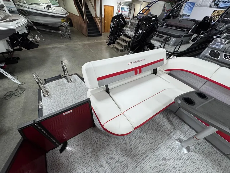 Slide: The Image of 2025 Bennington 24 ML boat interior with white seating and red accents in showroom. - 8