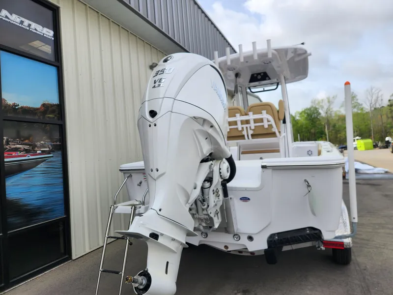 Slide: The Image of 2025 Sportsman Masters 247 Bay Boat with powerful outboard motor, parked near a building. - 5