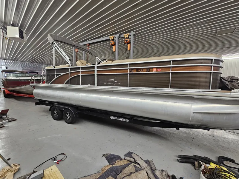 Slide: The Image of 2018 Bennington SX25 pontoon boat in a garage, on a trailer, with a metallic finish. - 0