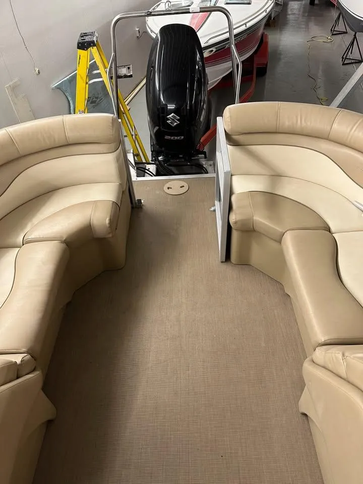 Slide: The Image of 2018 Bennington SX25 pontoon boat interior with beige seating and Suzuki outboard motor. - 11