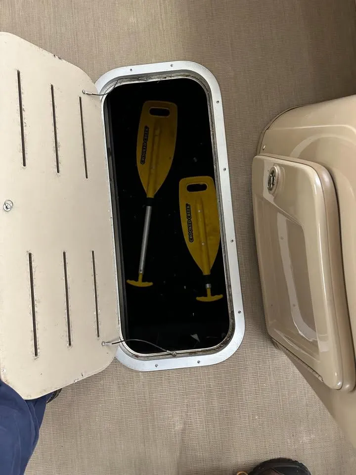 Slide: The Image of Open storage compartment on 2018 Bennington SX25 boat with yellow paddles inside. - 13