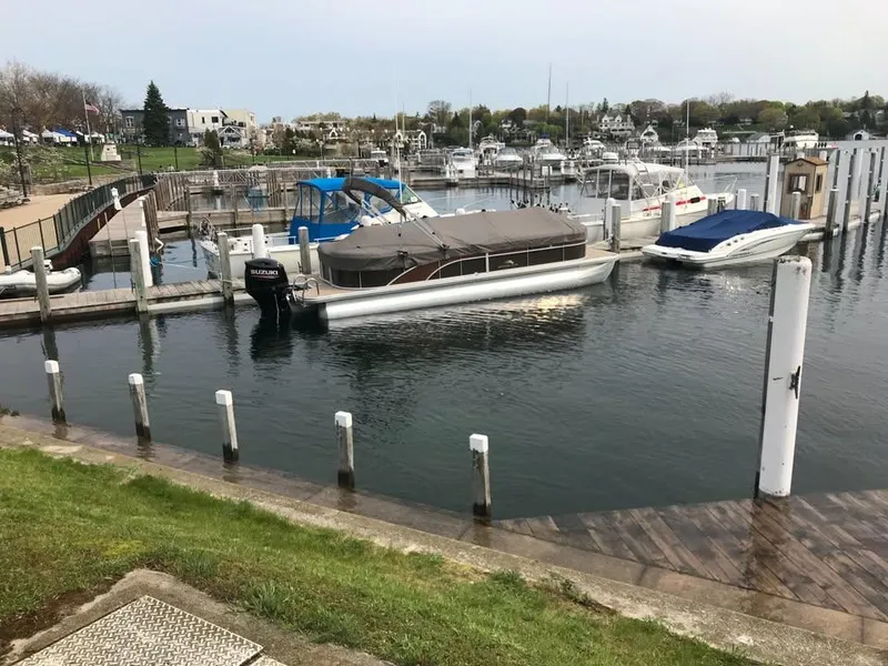 Slide: The Image of 2018 Bennington SX25 pontoon boat docked in a marina with other boats. - 2