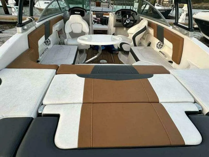 Slide: The Image of 2023 Chaparral 230 SSi boat interior with brown and white seating, table, and steering wheel. - 6