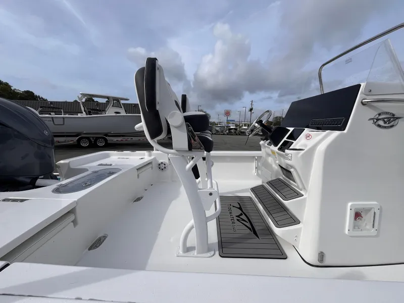 Slide: The Image of 2025 Tidewater 2110 Bay Max boat interior with seating and console, under a cloudy sky. - 5