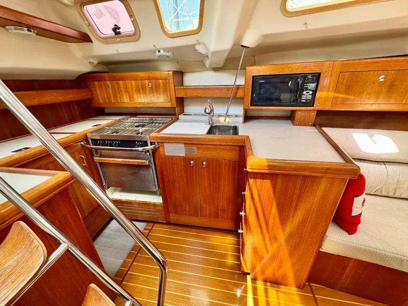Slide: The Image of 2003 Hunter Passage 420 yacht interior with wooden cabinetry, stove, sink, and microwave. - 32
