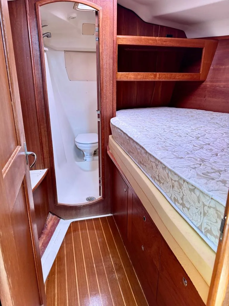 Slide: The Image of 2003 Hunter Passage 420 yacht interior with wooden finish, bed, and compact bathroom. - 38