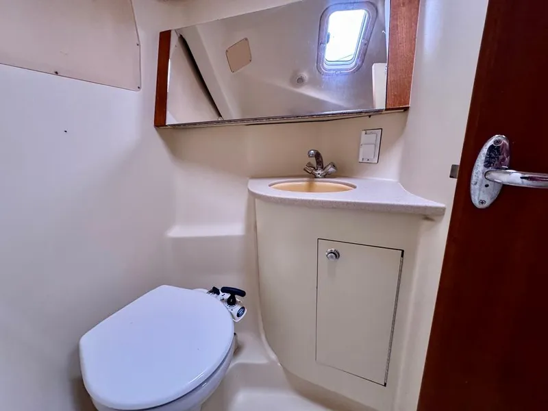 Slide: The Image of 2003 Hunter Passage 420 yacht bathroom with toilet, sink, mirror, and porthole window. - 42