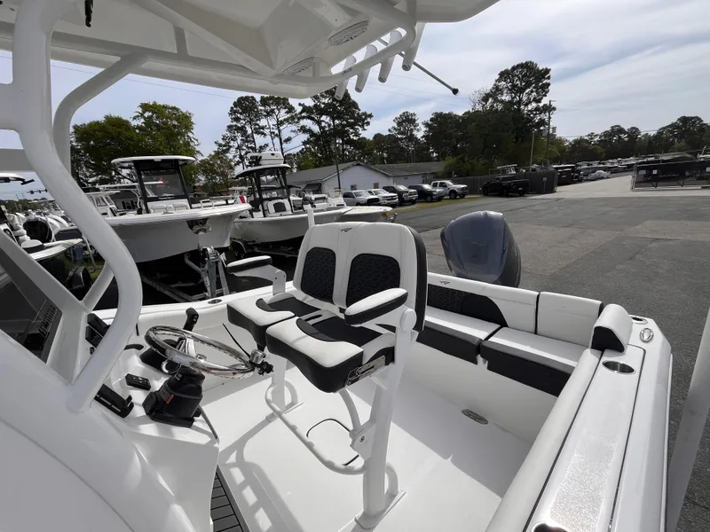 Slide: The Image of 2025 Tidewater 232 LXF boat interior with seating and steering wheel, parked outdoors. - 14