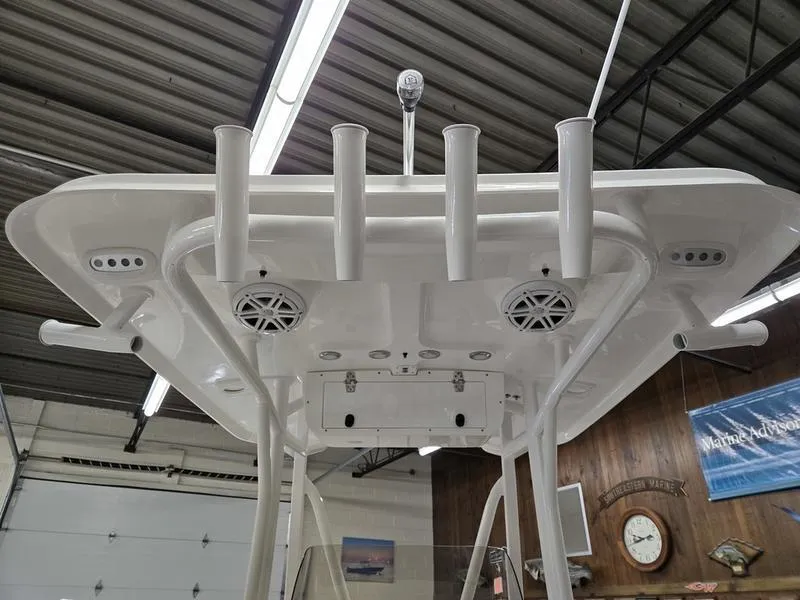 Slide: The Image of 2025 Sea Hunt Ultra 229 boat T-top with rod holders and speakers in a garage. - 13