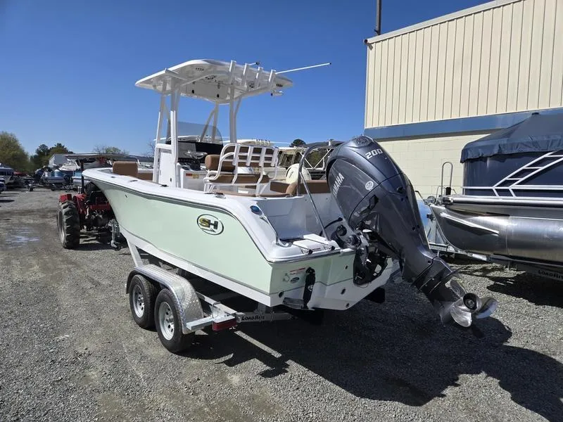 Slide: The Image of 2025 Sea Hunt Ultra 229 boat on trailer with outboard motor, parked outdoors. - 3