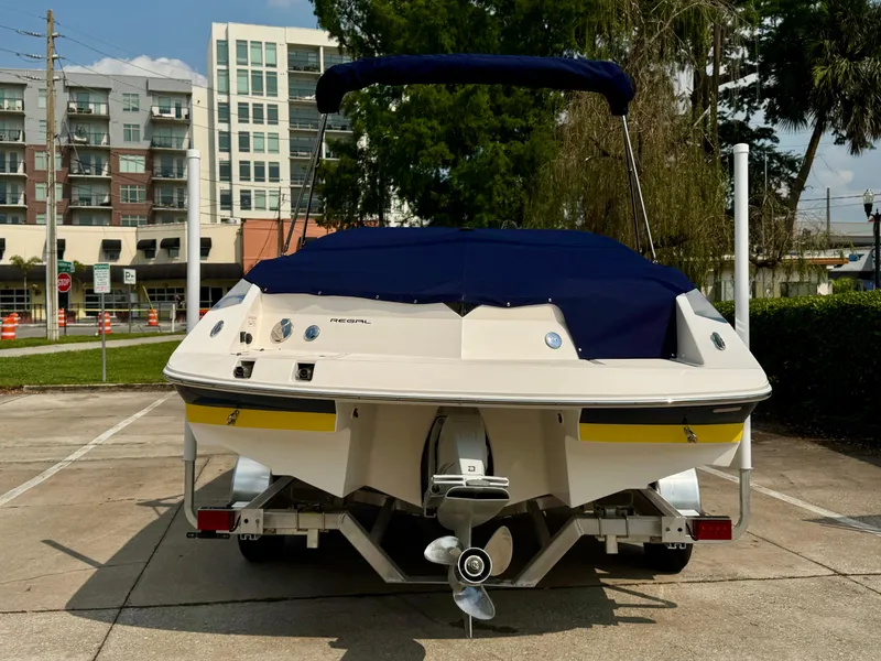 Slide: The Image of 2008 Regal 2200 Bowrider boat with blue cover, parked in urban setting. - 2
