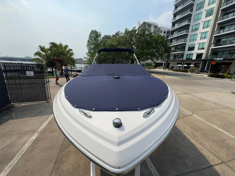 Slide: The Image of 2008 Regal 2200 Bowrider boat with blue cover, parked near modern buildings. - 3