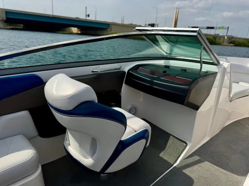 Slide: The Image of 2008 Regal 2200 Bowrider interior with blue and white seating, near a bridge on the water. - 8
