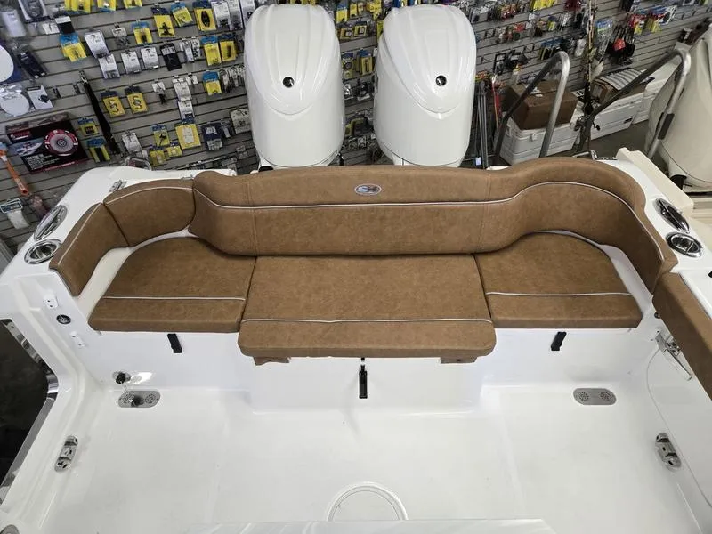 Slide: The Image of 2025 Sea Hunt Ultra 265SE boat with brown cushioned seating in a showroom. - 10