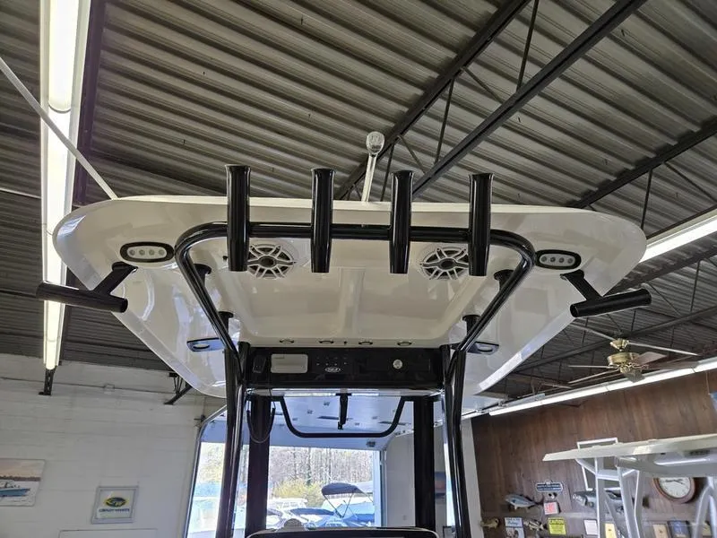Slide: The Image of 2025 Sea Hunt Ultra 265SE boat with rod holders and speakers in a showroom. - 18