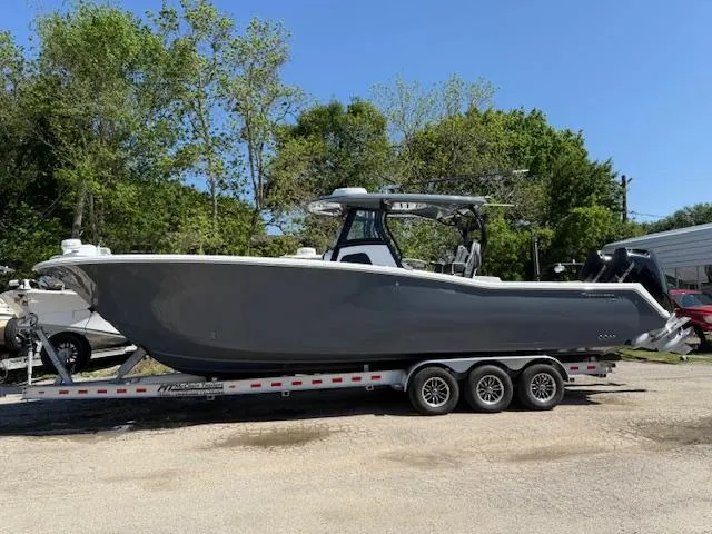 Slide: The Image of 2025 Tidewater 320 CC Adventure boat on a trailer, parked outdoors. - 0