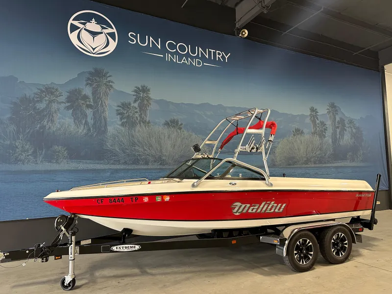 Slide: The Image of 2002 Malibu Sunsetter boat in showroom, red and white design, on trailer. - 2