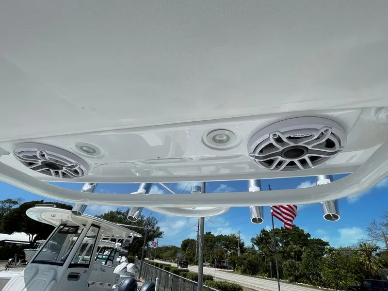 Slide: The Image of 2025 Everglades 273CC boat speakers and rod holders under canopy, clear sky background. - 17