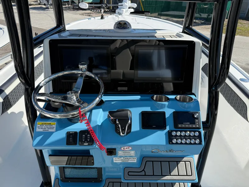 Slide: The Image of 2025 Tidewater 2700 Carolina Bay boat dashboard with steering wheel and electronic controls. - 2