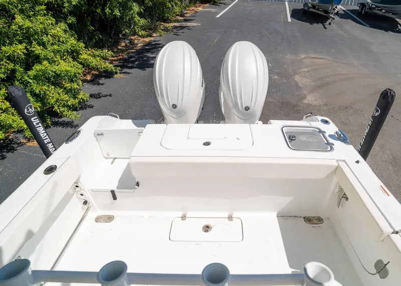 Slide: The Image of 2025 Sea Hunt Gamefish 25 boat with dual engines, parked on asphalt near greenery. - 9