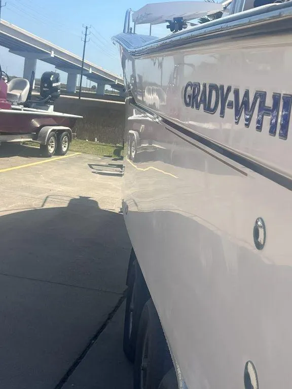 Slide: The Image of 2003 Grady-White 306 Bimini boat parked near a trailer in a sunny setting. - 10