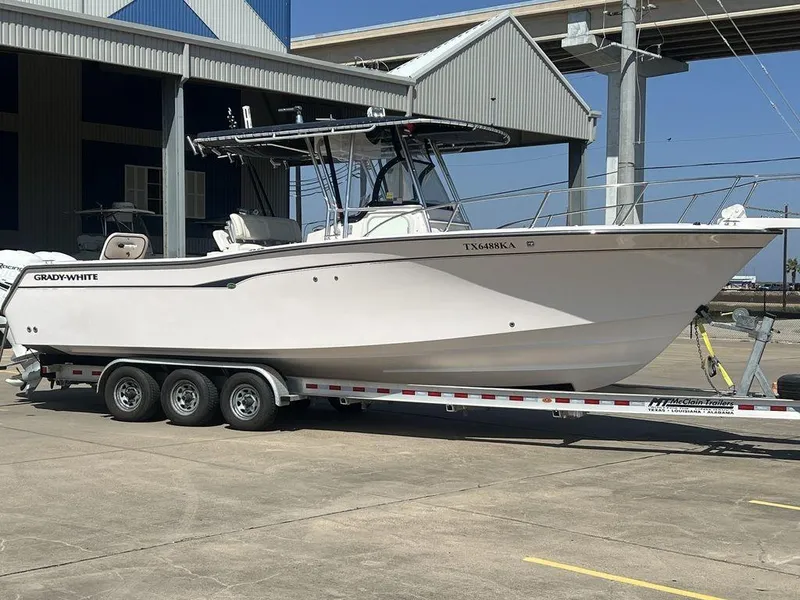 Slide: The Image of 2003 Grady-White 306 Bimini boat on trailer, parked near a marina. - 14