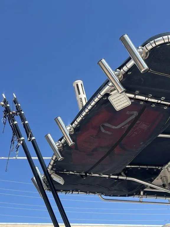 Slide: The Image of 2003 Grady-White 306 Bimini boat with fishing rod holders against clear blue sky. - 17