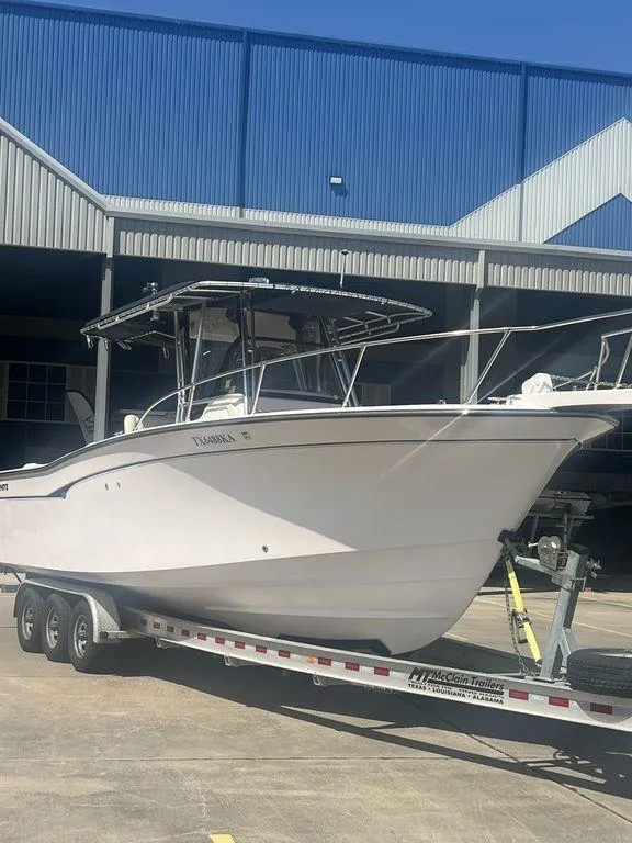 Slide: The Image of 2003 Grady-White 306 Bimini boat on trailer, parked outside a blue industrial building. - 2