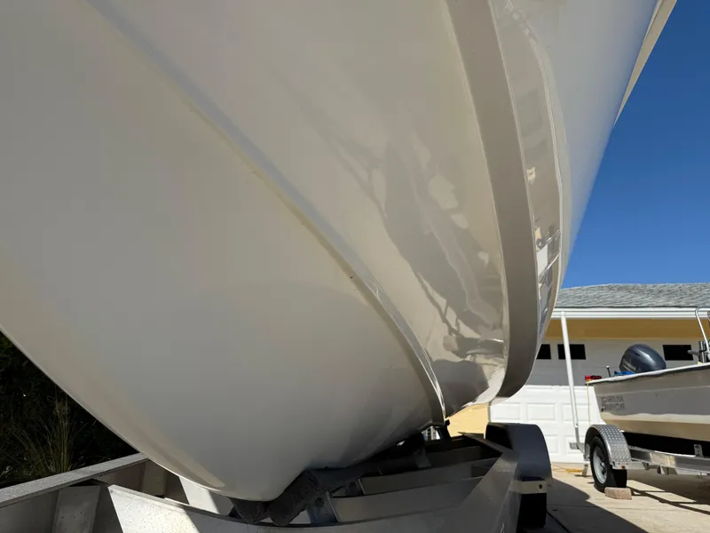 Slide: The Image of 2020 Cape Horn 27 XS boat hull on trailer, parked in driveway under clear blue sky. - 3