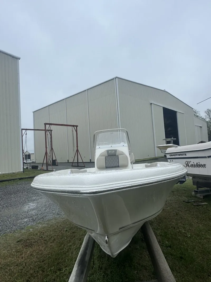 Slide: The Image of 2025 Key West 179 FS boat on trailer near large storage building. - 2