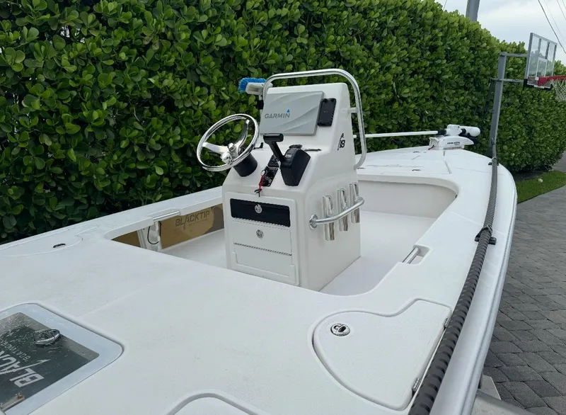 Slide: The Image of 2022 Blacktip Boatworks 18 Flats boat with steering console, surrounded by greenery. - 3