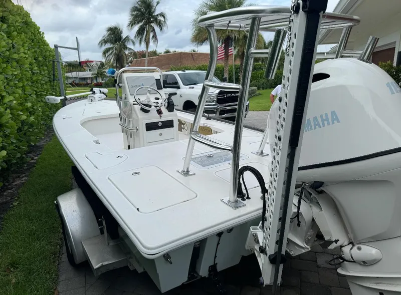 Slide: The Image of 2022 Blacktip Boatworks 18 Flats boat with Yamaha engine, parked on a trailer, surrounded by palm trees. - 5