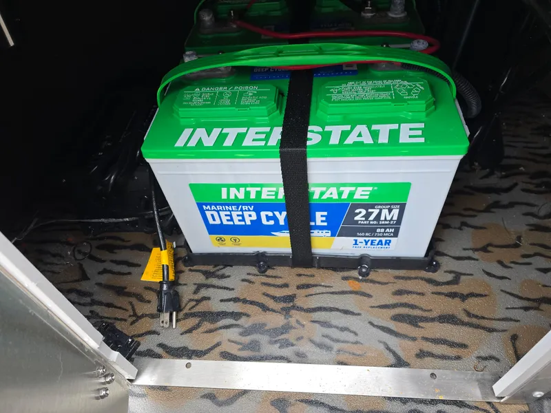 Slide: The Image of Interstate marine deep cycle battery in Xpress H190B, 2025 model, secured with strap. - 12